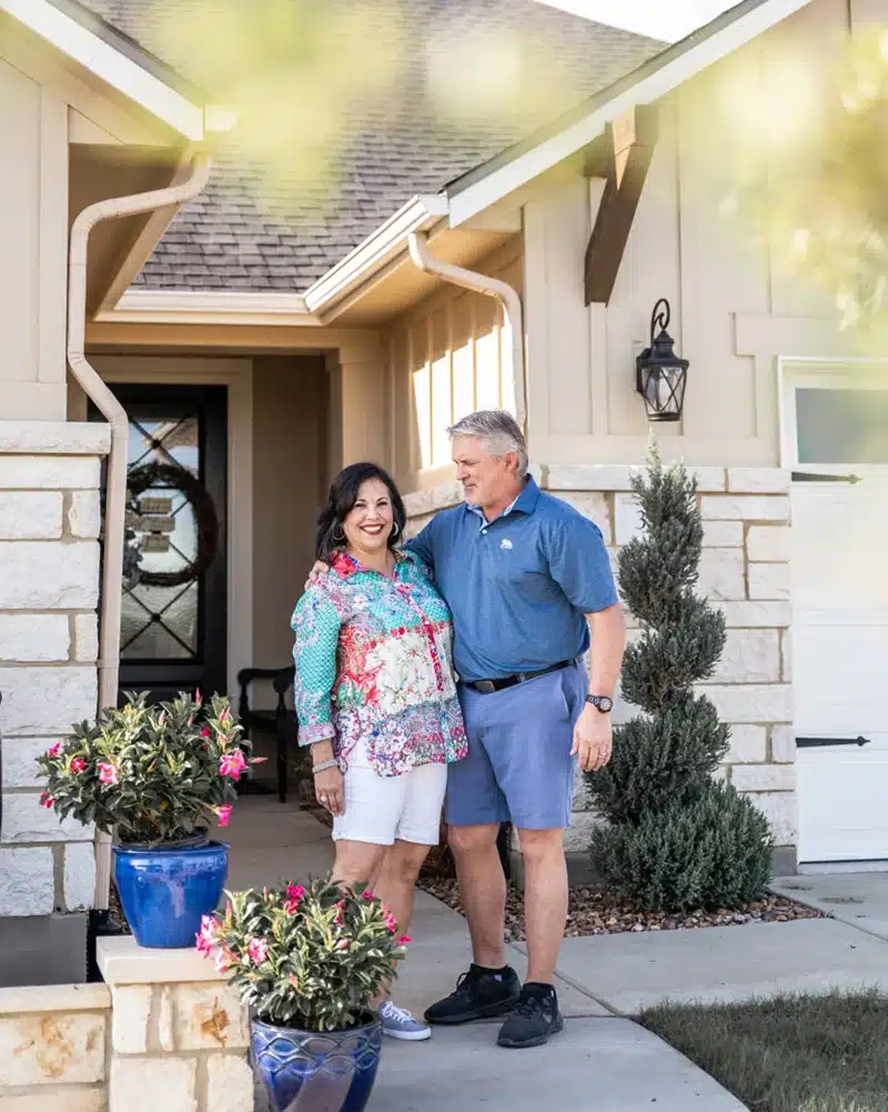 couple in front of new home at kissing tree