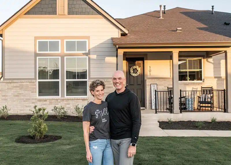 couple in front of new home at kissing tree