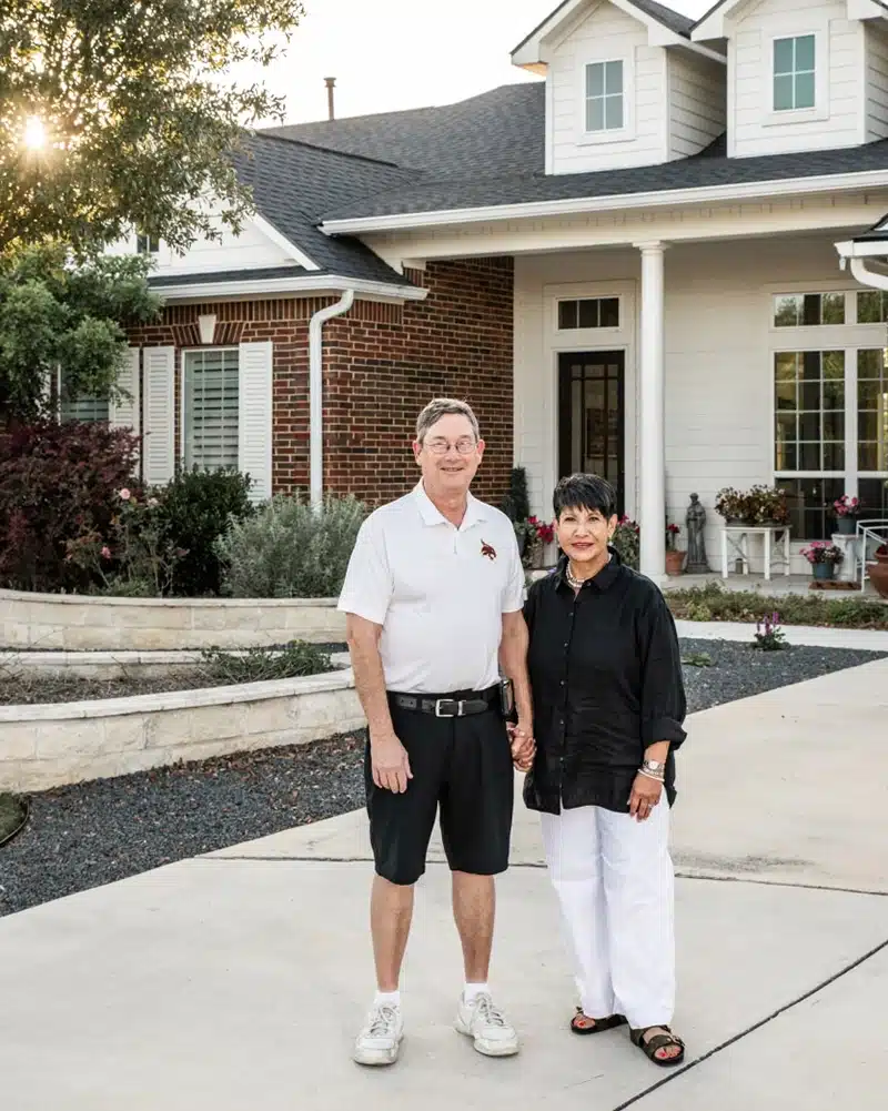 couple in front of new home at kissing tree